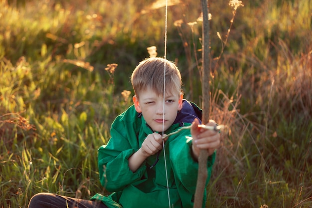 Портрет молодой мальчик, стрелять с ручной лук и стрелы на цель на закате, летом на открытом воздухе.