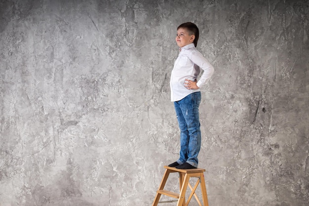 Portrait of a young boy standing on a chair isolated on a white background in the studio