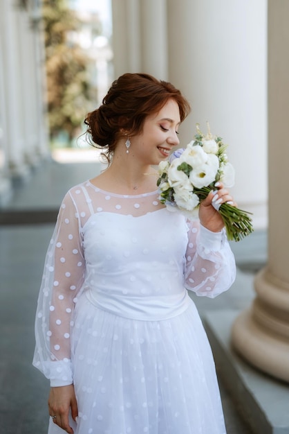 Portrait of a young bride girl in a light dress in an urban environment