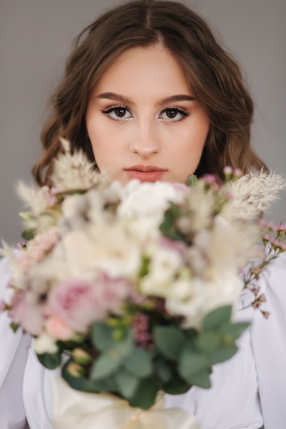 Ritratto di giovane sposa con bouquet da sposa davanti a sfondo grigio studio photophoot