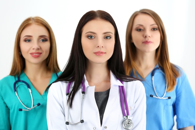 Portrait of young brunette female doctor surrounded by medical team, posing. Healthcare and medicine concept.