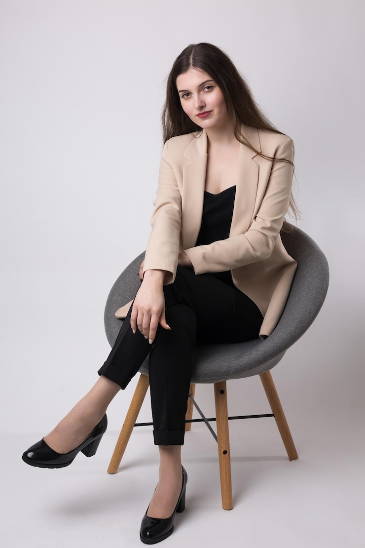 Portrait of a young brunette with long hair in the studio Cute girl sitting on a chair on a white background