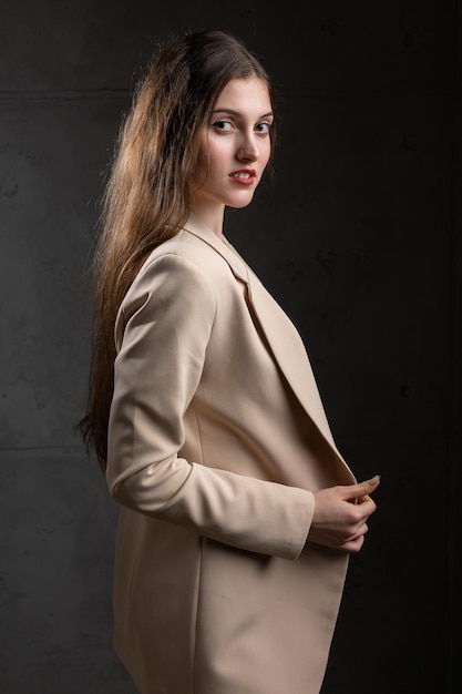 Portrait of a young brunette with long hair in the studio Dramatic photo in dark colors