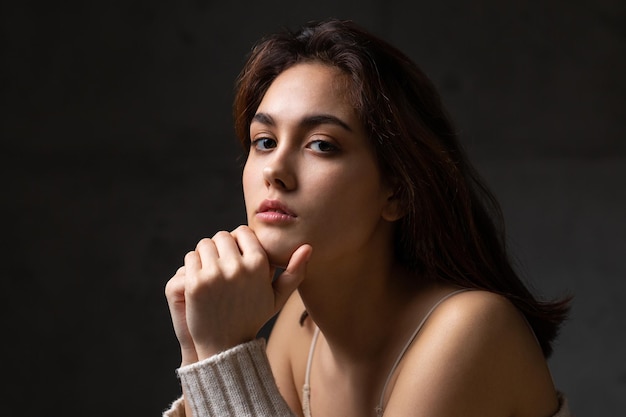 Portrait of a young brunette with long hair in the studio Dramatic photo in dark colors