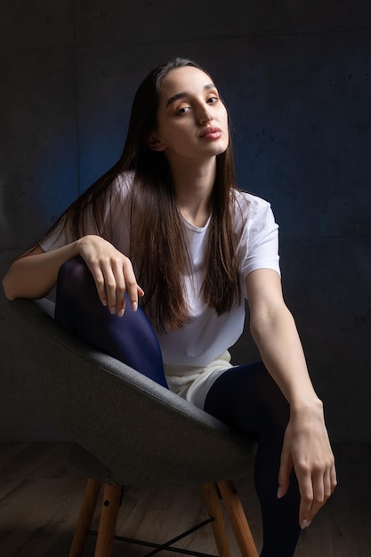 Portrait of a young brunette with long hair in the studio Dramatic photo in dark colors