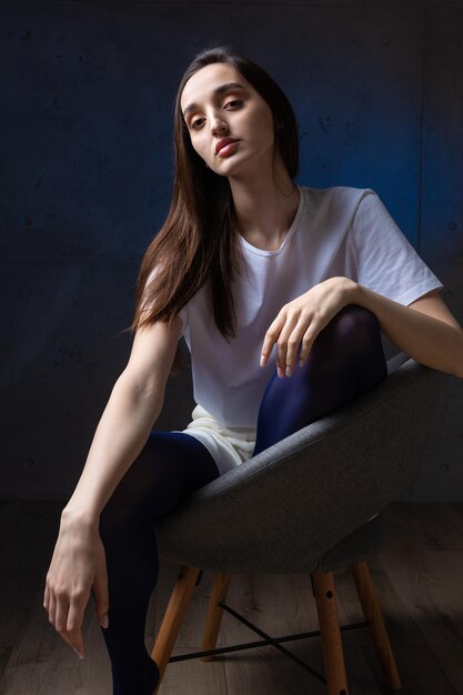 Portrait of a young brunette with long hair in the studio Dramatic photo in dark colors