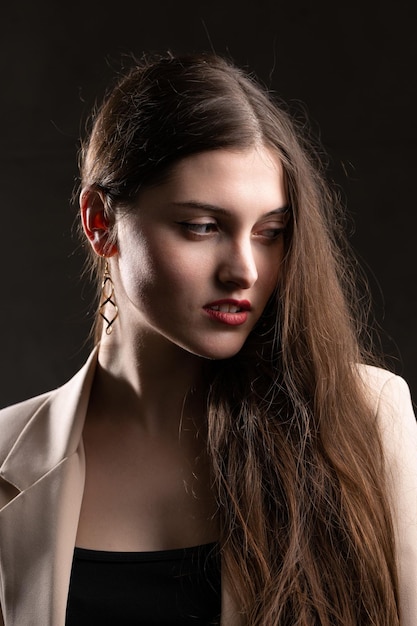 Portrait of a young brunette with long hair in the studio Dramatic photo in dark colors