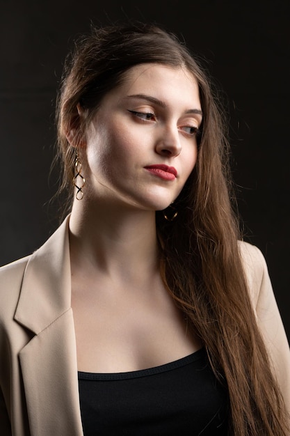 Portrait of a young brunette with long hair in the studio Dramatic photo in dark colors