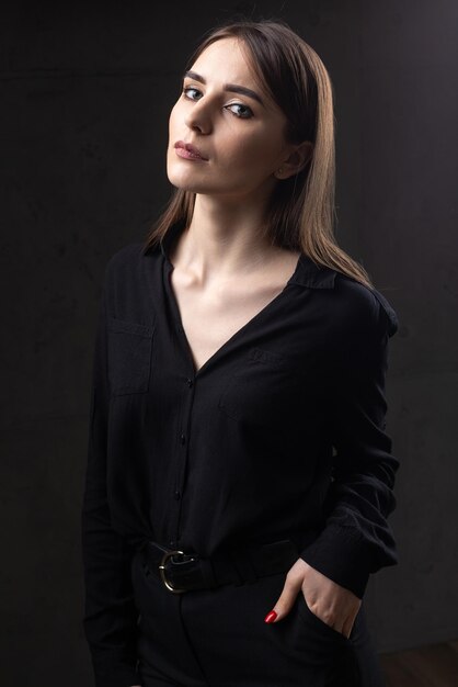 Portrait of a young brunette with long hair in the studio Dramatic photo in dark colors