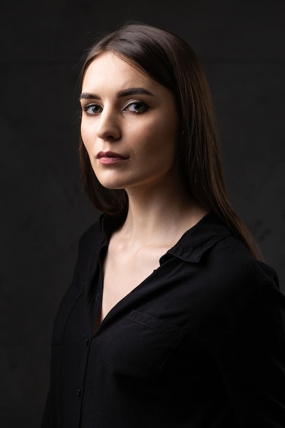 Portrait of a young brunette with long hair in the studio Dramatic photo in dark colors