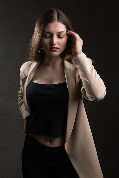 Portrait of a young brunette with long hair in the studio Dramatic photo in dark colors