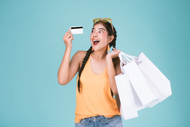 Photo portrait of young brunette woman holding credit card and shopping bags