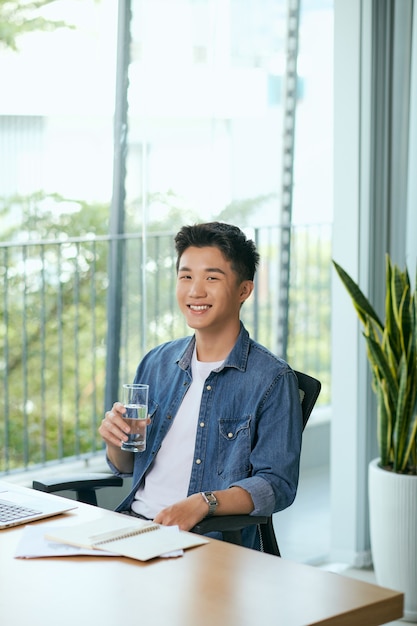 Portrait of a young business man using laptop computer while and smartphone working.