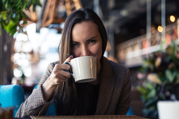 Portrait of a young business woman drinking tea from a Cup closeup with blurred restaurant