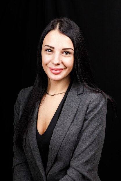 Portrait of young business woman in  a grey jacket on black.