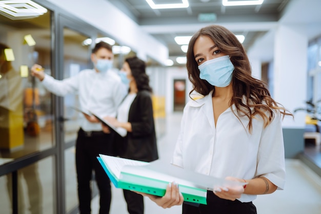 Portrait of young business woman in protective face mask an office building hallway.