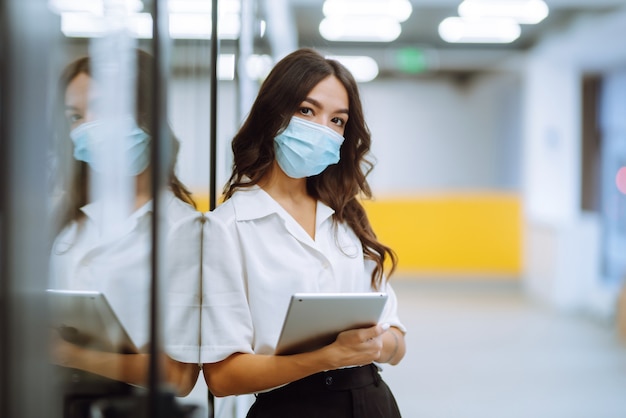 Portrait of young business woman in protective face mask an office building hallway.