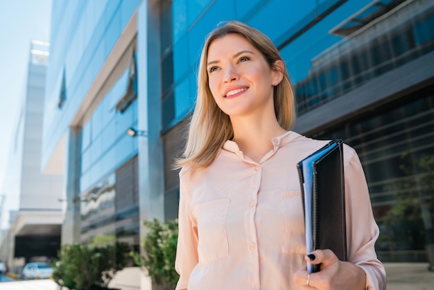 Portrait of young business woman standing outside office buildings