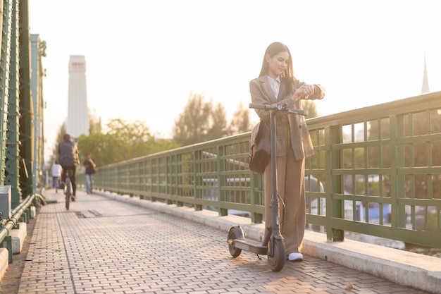 Portrait of young business woman with an electric scooter to work over bridge