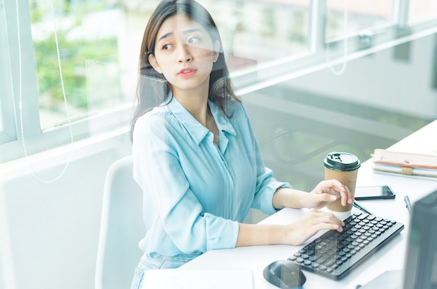 Portrait of young business woman working and looking out the window