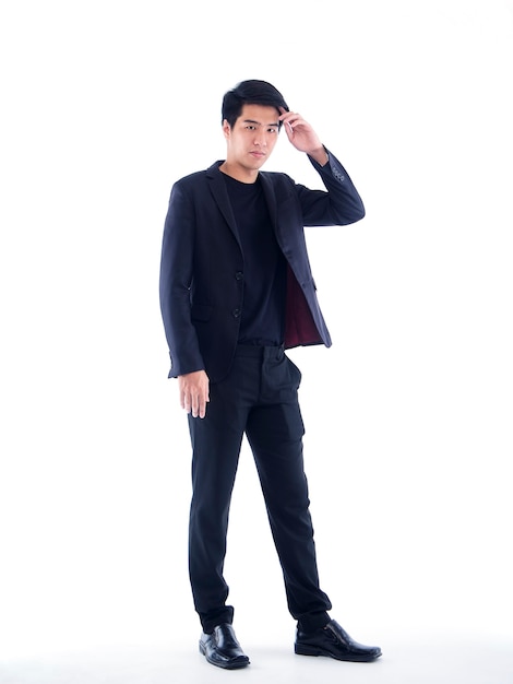 Portrait of young businessman in black suit on white wall