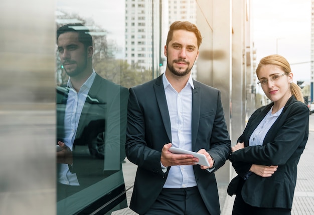 Portrait of a young businessman and businesswoman standing near the corporate building