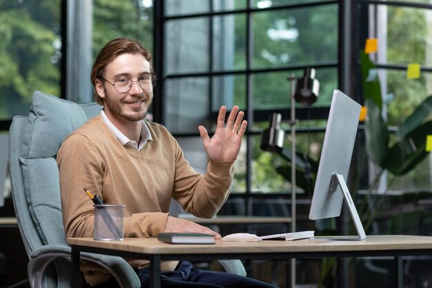 Portrait of a young businessman designer programmer in a busy office sitting at a table with a