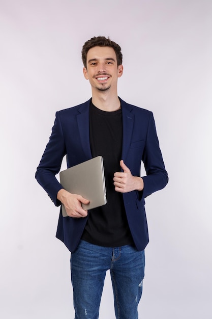 Портрет молодого бизнесмена счастливой позитивной улыбкой, держащего ноутбук изолированным на белом фоне