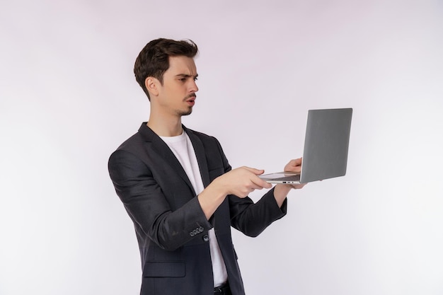 Portrait of young businessman has computer problems and is holding a laptop isolated on white background