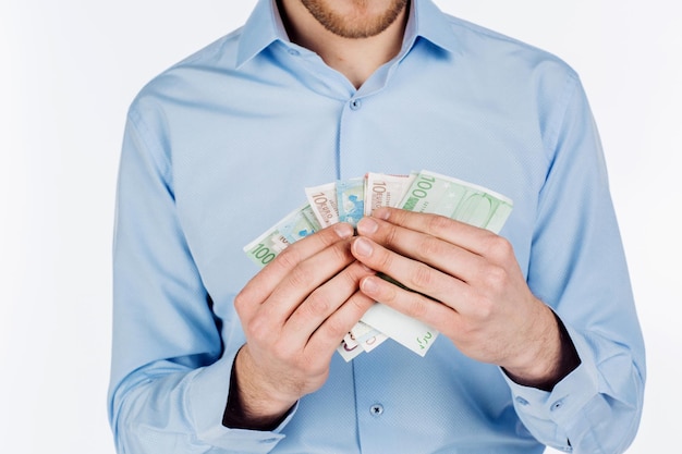 Portrait of young businessman holding and counts money dollar bills in hands isolated on white background emotion facial expression feeling financial reward savings