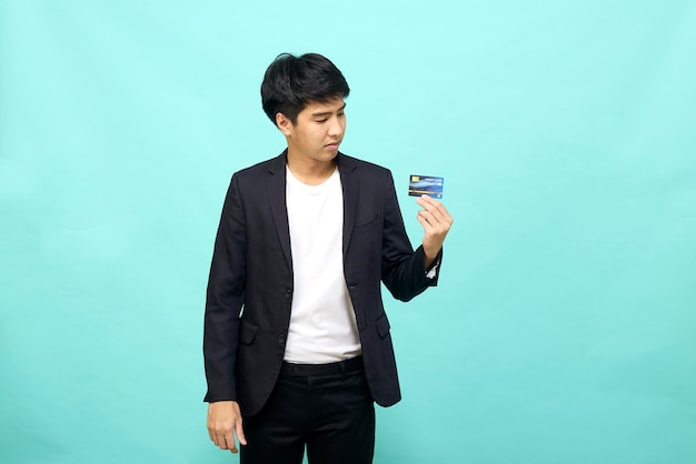 Portrait of young businessman Holding and showing credit card on hand on Isolated blue background