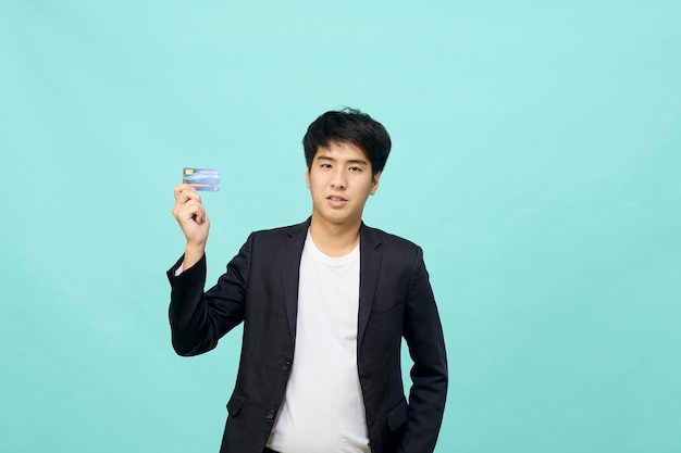 격리 된 파란색 배경에 신용 카드를 들고 보여주는 젊은 사업가의 초상화