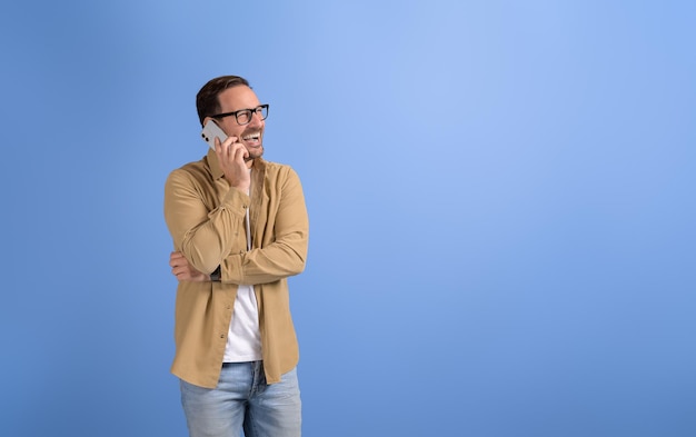Foto ritratto di un giovane uomo d'affari che ride e comunica tramite telefono cellulare sullo sfondo blu
