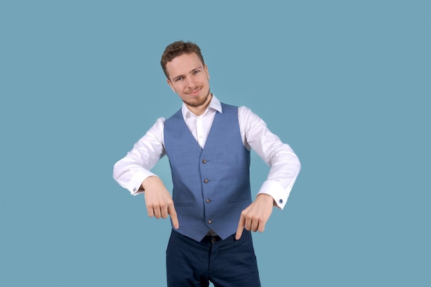 Portrait young businessman pointing his fingers down Isolated on blue