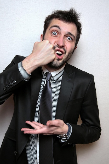 Photo portrait of young businessman punching against wall