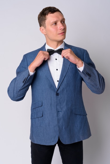 Portrait of young businessman wearing blue suit against white wall