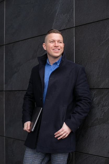 Portrait of young businessman with expensive laptop in hands blue shirt jeans smiling keeping hands