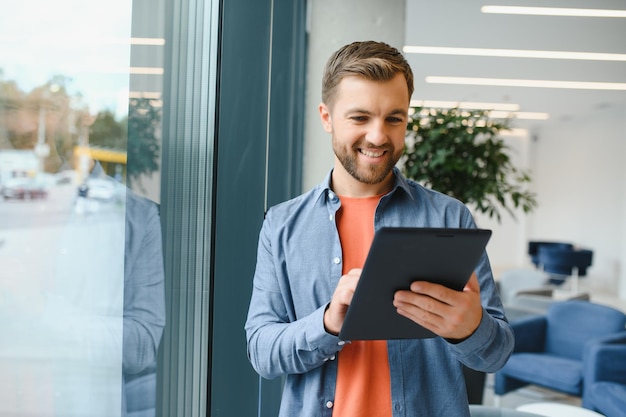 Portrait of young businessman with tablet standing in an office working