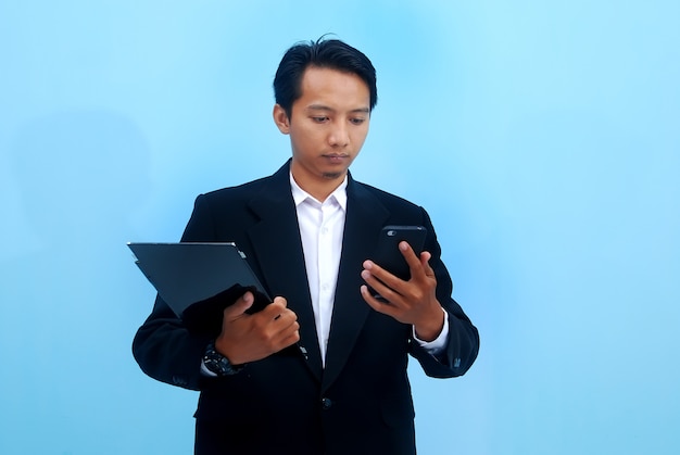 Foto ritratto di un giovane uomo d'affari guardando lo sviluppo della sua attività attraverso schede e smartphone
