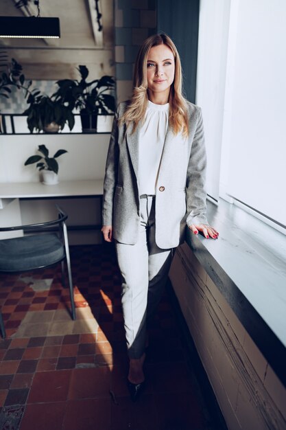 Portrait of a young businesswoman in formal outfit standing near window in office