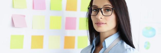 Portrait of young businesswoman in glasses on background of white board