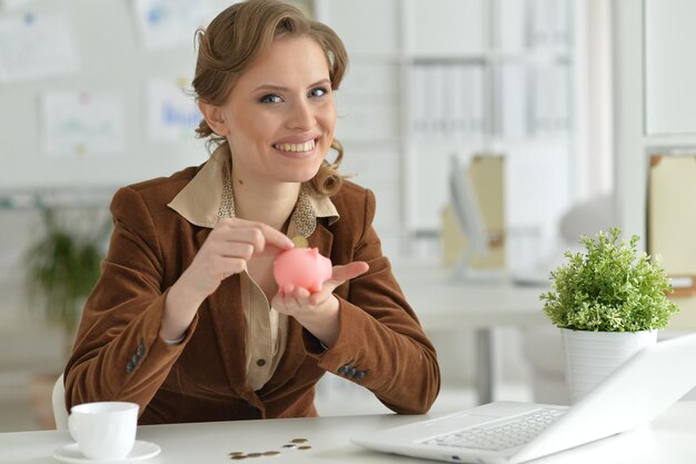 Portrait of young businesswoman holding piggy bank