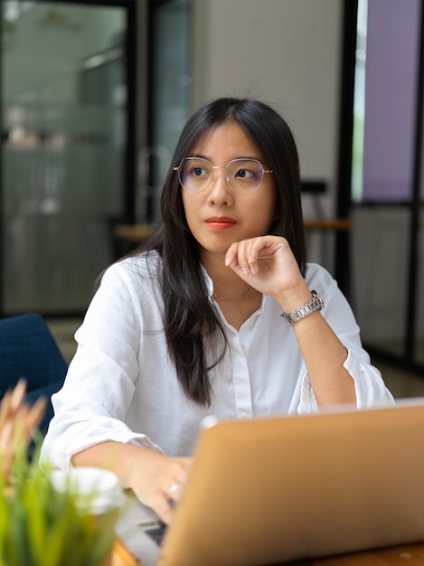 Portrait of young businesswoman looking of the window while thinking about her project