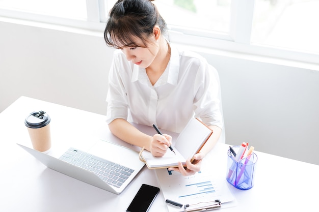 Portrait of young businesswoman sitting and making plans in a notebook