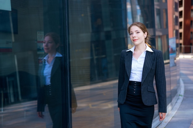 オフィスセンターの近くの通りに若い女性実業家の肖像画。黒のジャケットと白のシャツで