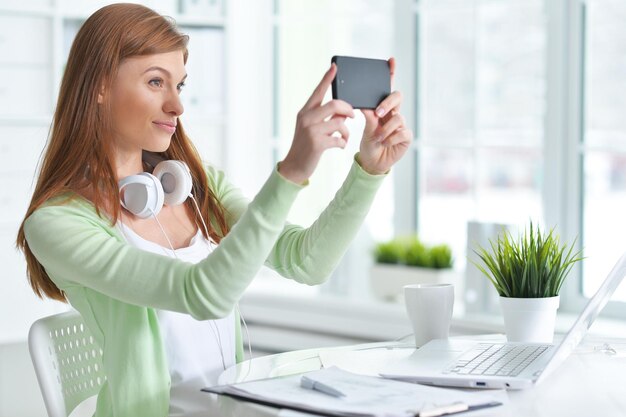 Portrait of young businesswoman taking selfie in the office