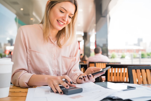Портрет молодой бизнес-леди, используя свой мобильный телефон во время работы в кафе. Кафе. Бизнес-концепция.
