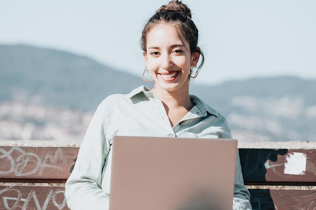 Portrait of young businesswoman using laptop while sitting against sky