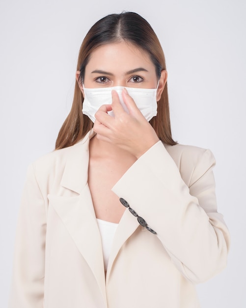 Portrait of young businesswoman wearing a surgical mask over white background studio