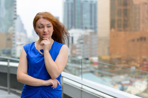 Portrait of young businesswoman with red hair in the city